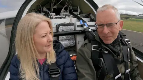 Reporter Katharine Da Costa sitting next to Dr Bill Brooks in the cockpit of the Axe on the runway