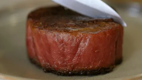 Sirloin steak being cut with a knife
