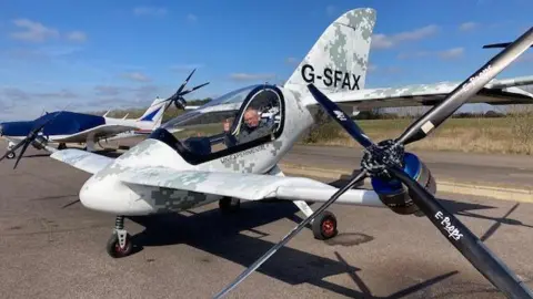 BBC The Skyfly Axe two-seater aircraft with two wings and four rotor blades sitting on an airfield