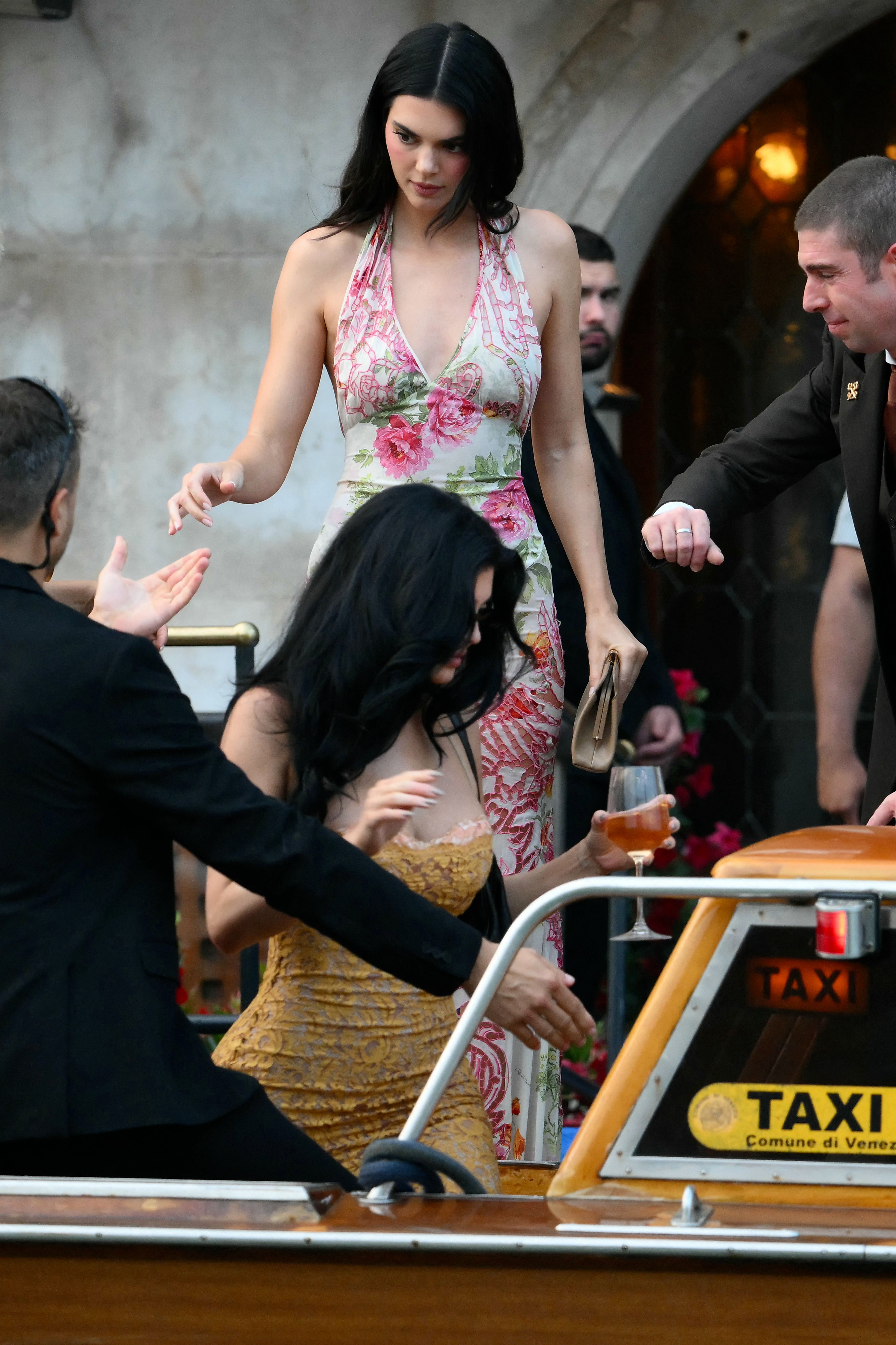 Kendall Jenner kicked off her ‘euro summer’ in the perfect halter dress. As she headed to Bezos’ welcome party, she wore a pink and green floral gown, with a tan clutch in hand